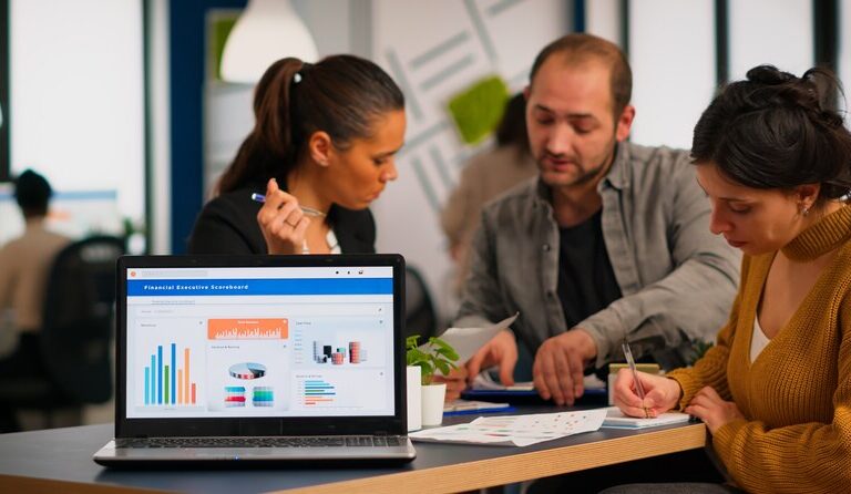 Marketing intern analyzing digital strategy on a laptop in a collaborative workspace.