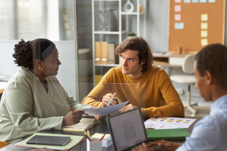 An intern analyzing reports and discussing findings in a business team meeting.