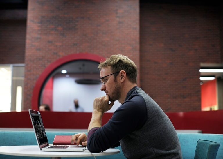 Young professional intern working on a laptop in a corporate office.