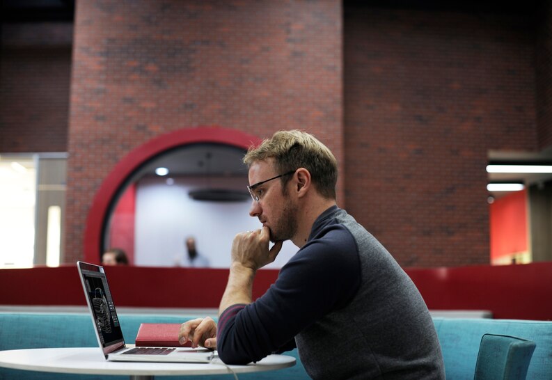 Young professional intern working on a laptop in a corporate office.
