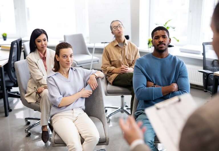 A diverse group of people discussing mental health awareness in a professional setting.
