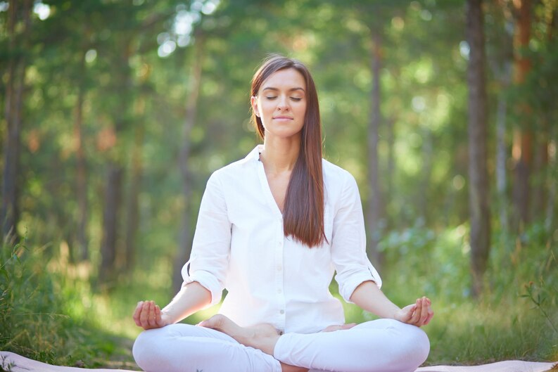 A woman practicing mindfulness meditation in nature.