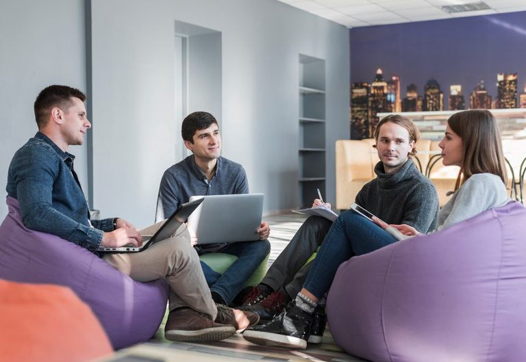 A group of young professionals receiving mentorship and hands-on training in a modern office environment.
