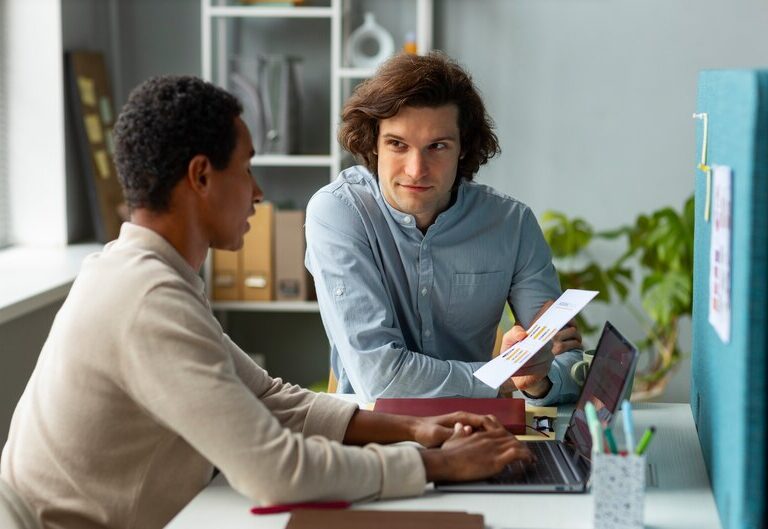 A young student intern working in a professional office, guided by an experienced mentor.