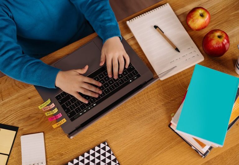 Student planning their schedule with books and laptop